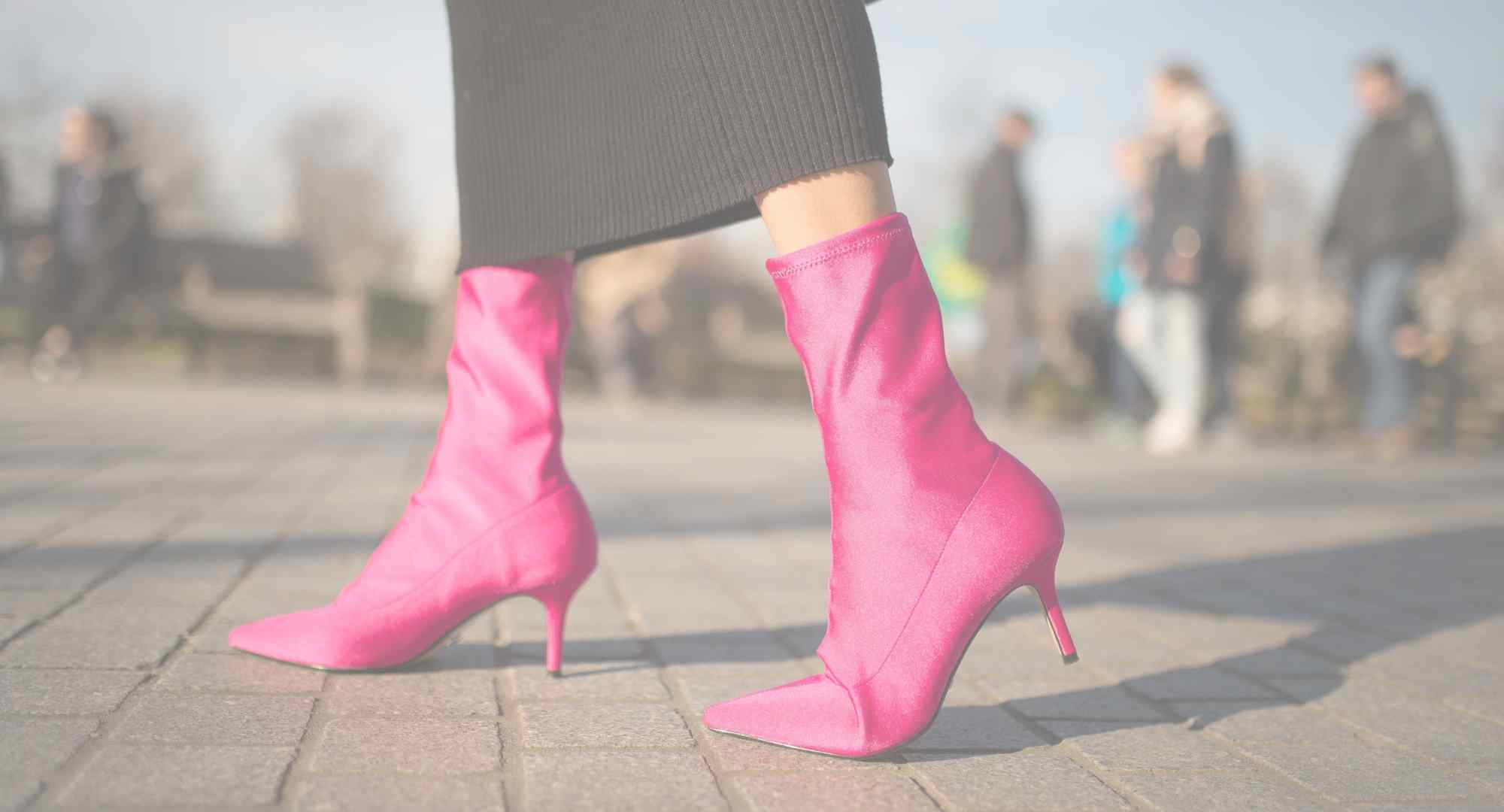 close up of woman's feet walking in a hot pink pointed toe ankle boots and black pants.