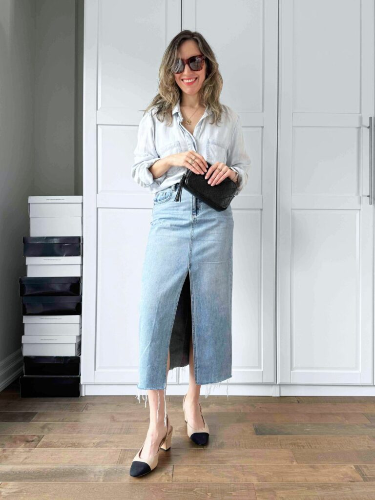 Woman posing in front of a white closet wearing a light denim shirt styled with midi denim skirt.