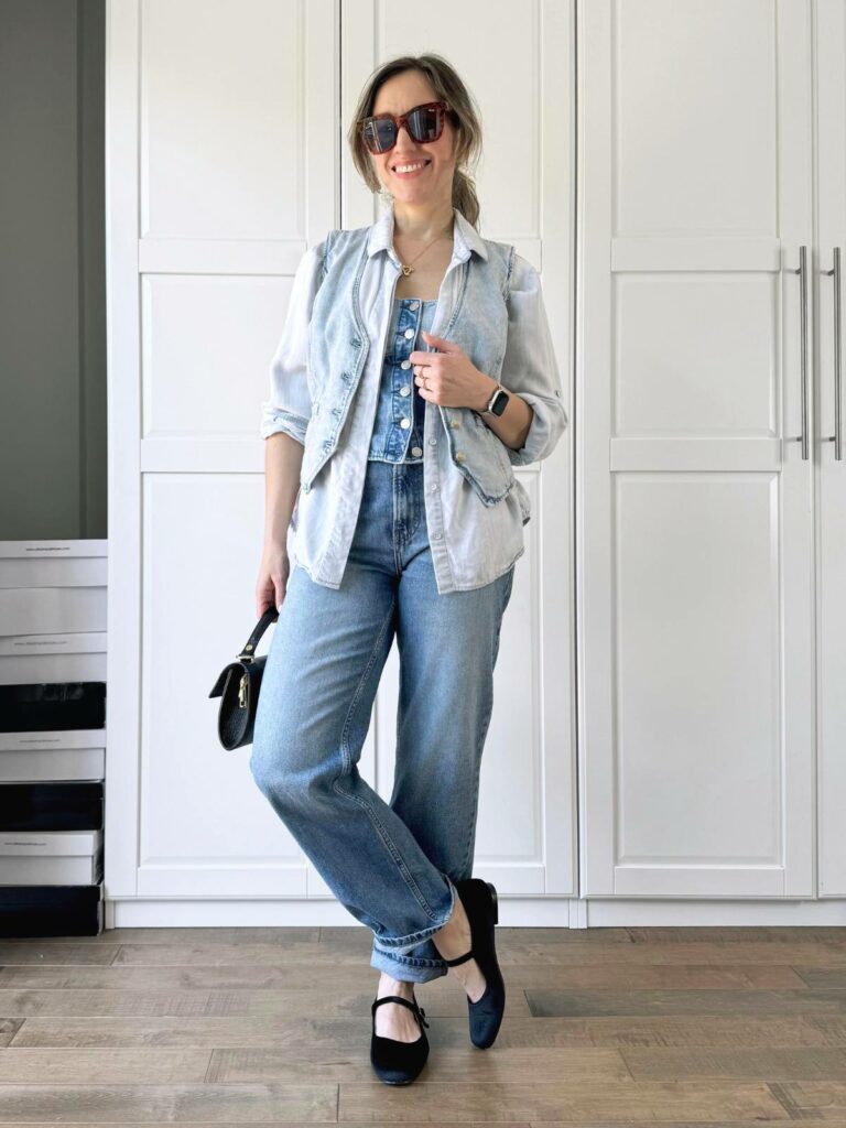 Woman posing in front of a white closet wearing a light denim vest styled with leyered darker denim vest and lighter denim shirt and jeans.