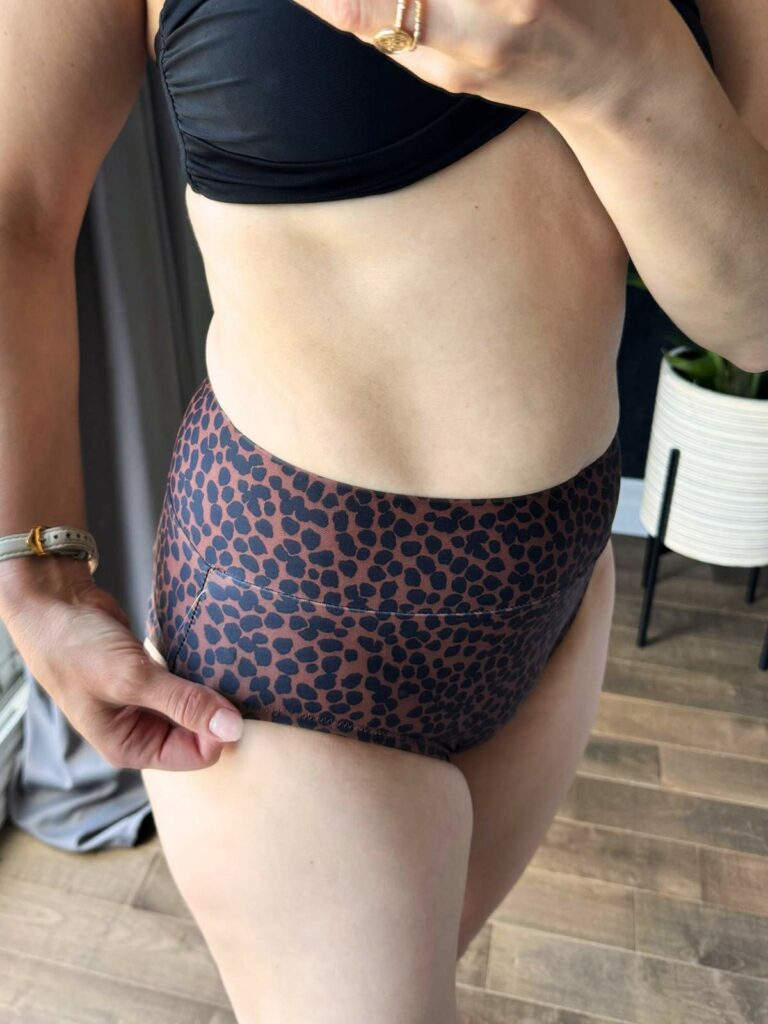 Closeup of Woman posing in front of a mirror wearing leopard print high waisted bikini bottoms.