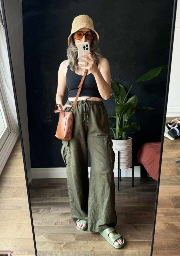 Woman posing wearing a black crop top with green wide leg pants.