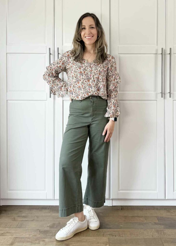 Woman posing wearing olive green pants with foral blouse.