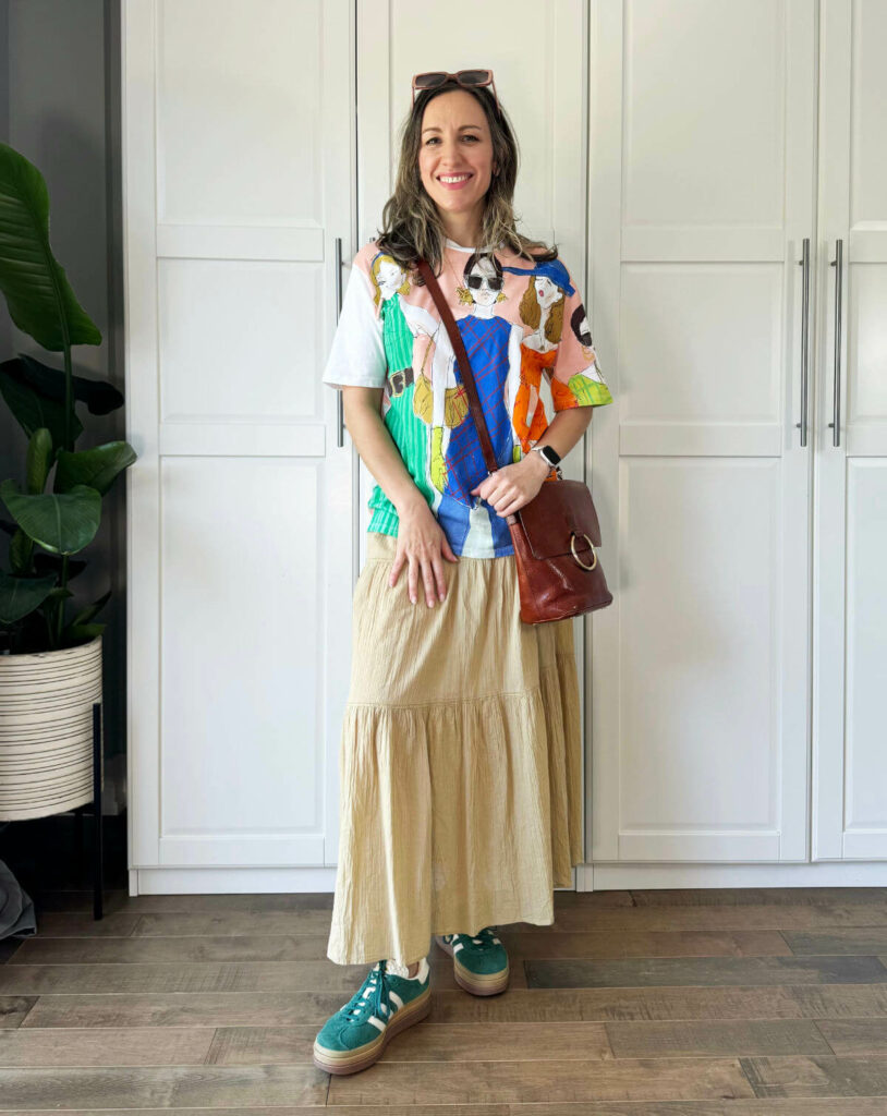 Woman posing wearing a graphic t-shirt outfit with a tiered maxi skirt.