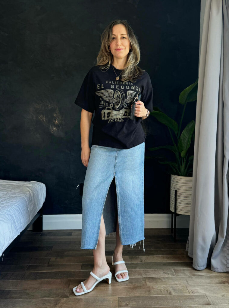 Woman posing wearing a graphic t-shirt outfit with a denim skirt.