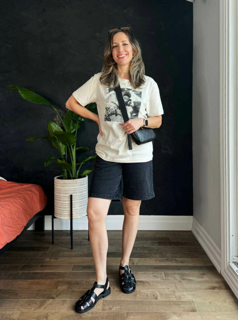 Woman posing wearing a graphic t-shirt outfit with black jorts.