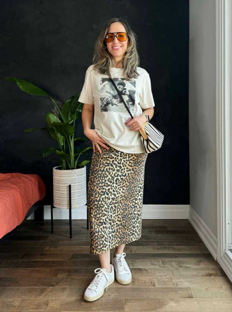 Woman posing wearing a graphic t-shirt outfit with leopard print skirt.