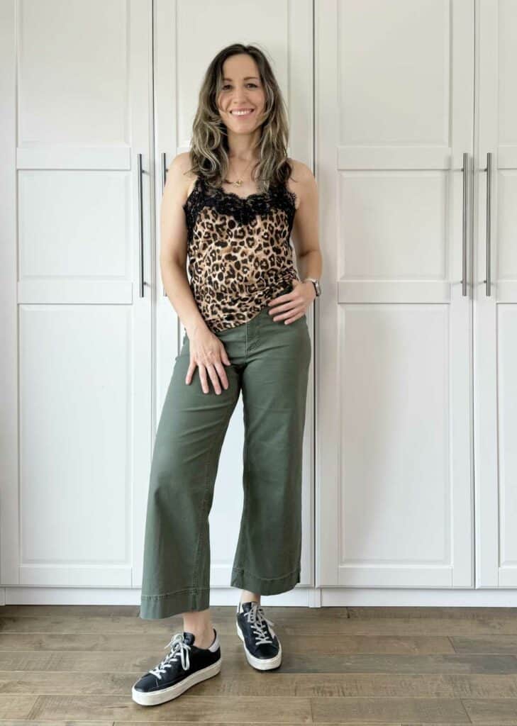 Woman posing wearing olive green pants with leopard print top.