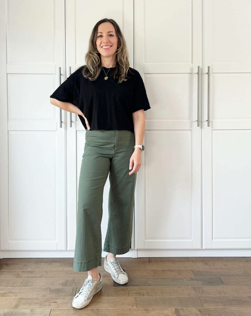 Woman posing wearing olive green pants with black top.