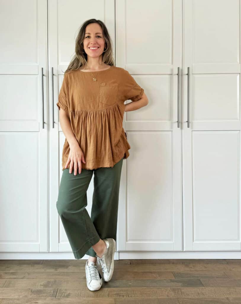 Woman posing wearing olive green pants with camel top.