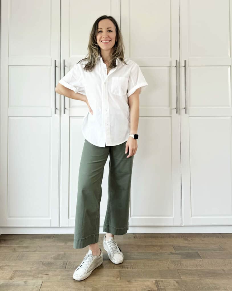 Woman posing wearing olive green pants with optic white top.