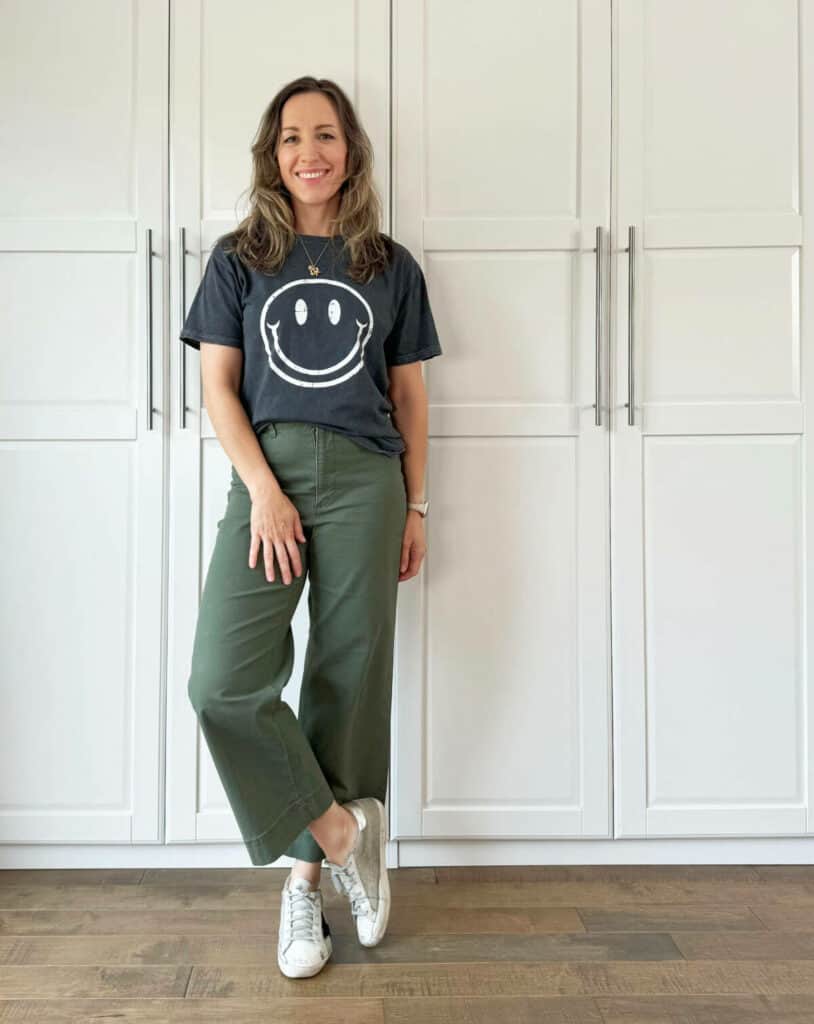 Woman posing wearing olive green pants with dark gray top with a print.