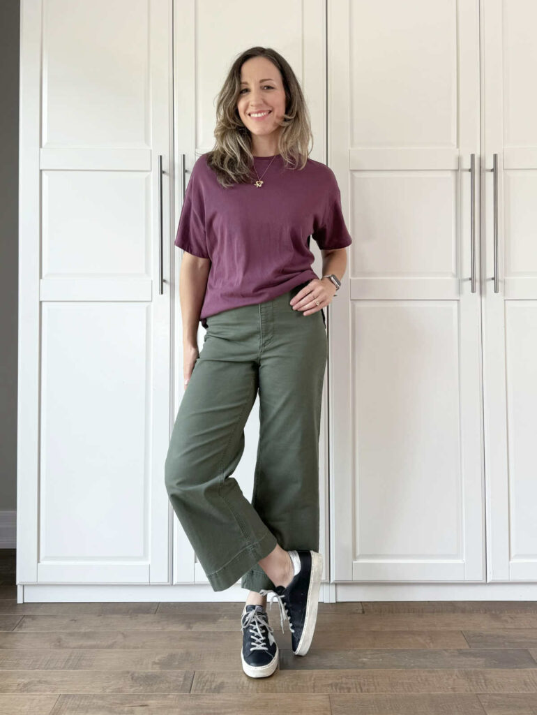 Woman posing wearing olive green pants with eggplant top.