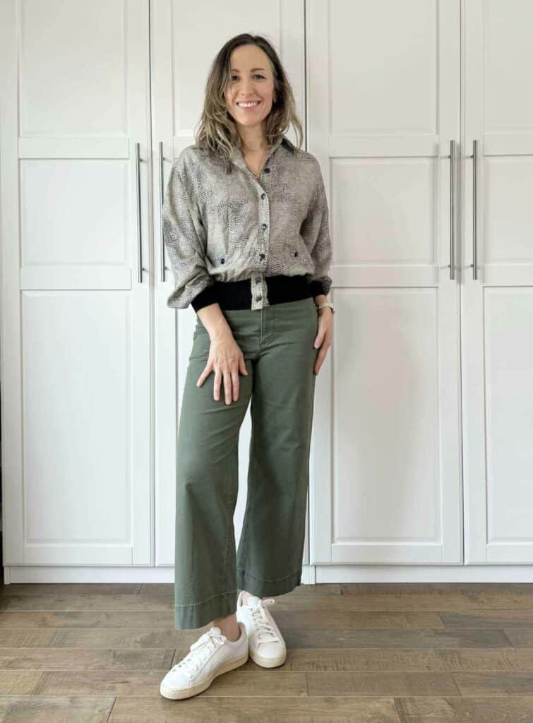 Woman posing wearing olive green pants with snake print top.