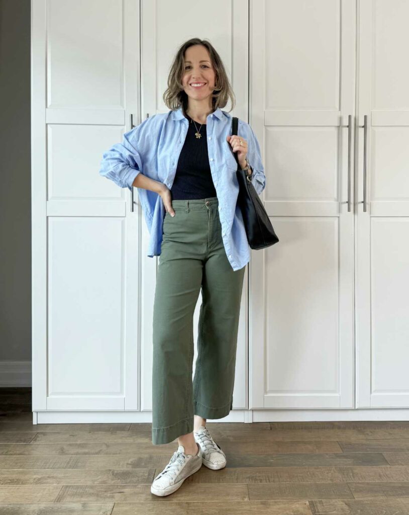 Woman posing wearing casual outfit consisting of olive green pants for fall with a blue shirt and white sneakers.