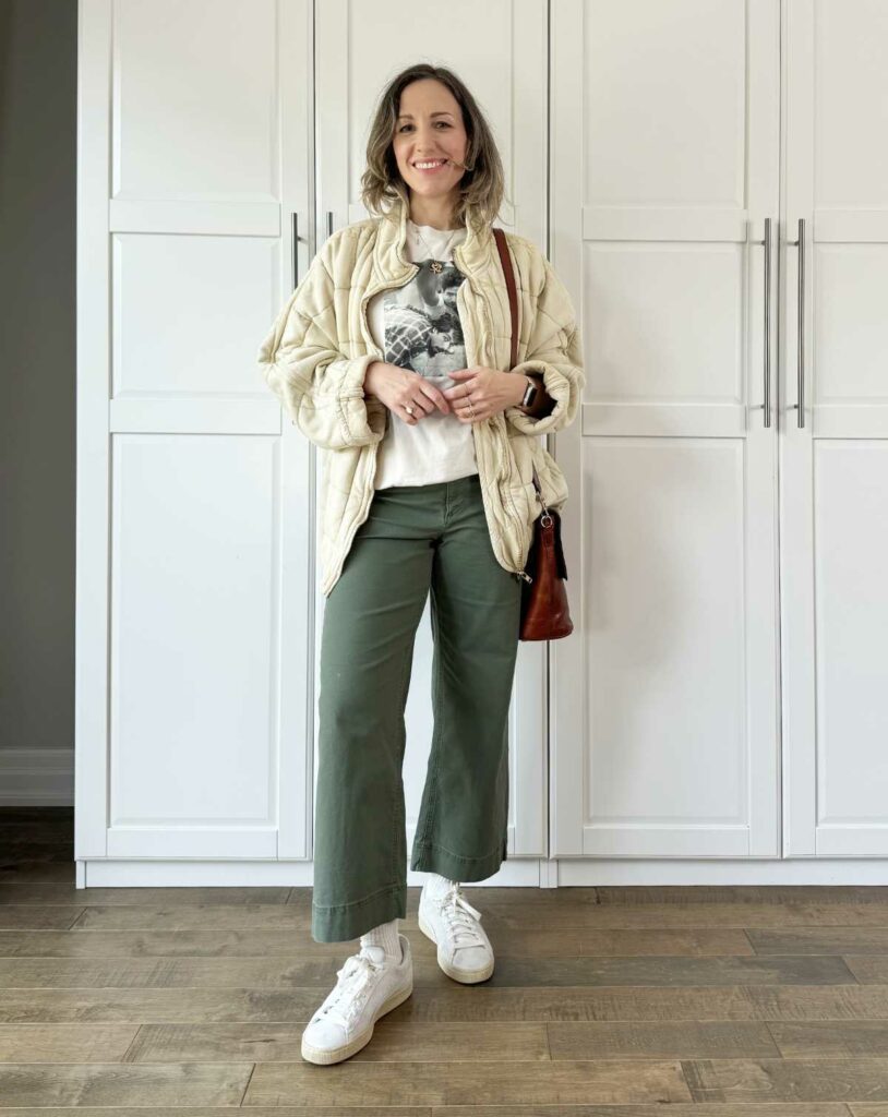 Woman posing wearing olive green pants for fall with a quilted jacket.