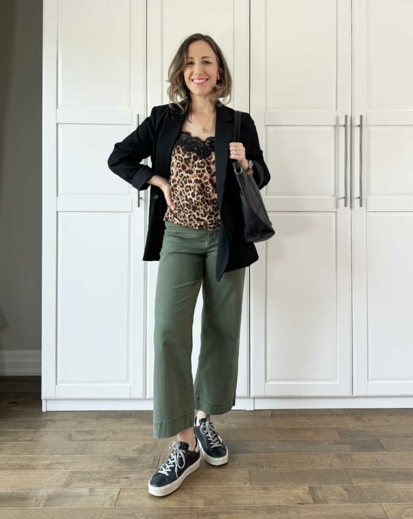 Woman posing wearing smart casual outfit consisting of olive green pants for fall with a blazer, leopard print top + sneakers.