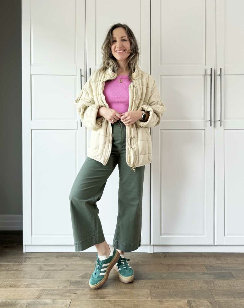 Woman posing wearing olive green pants for fall with a quilted jacket.